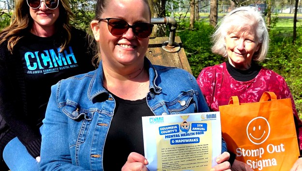 Columbia County Mental Health's Trish Tyler and Heather Petersen pose with National Alliance on Mental Illness's Judy Thompson holding flyers and merchandise for the Columbia County Mental Health Fair.
